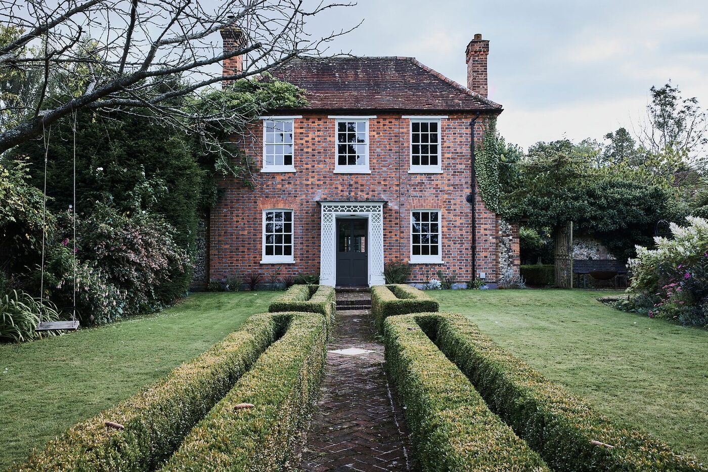 Traditional red-brick British house with a neat lawn and hedges